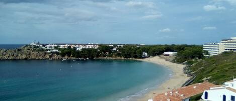 A coastal town with buildings along the beach, a clear sky, and calm sea.