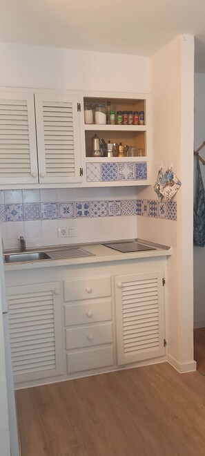 Una cocina con armarios blancos, salpicadero de azulejos y suelo de madera.