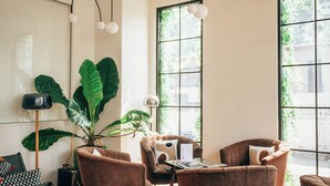 Een moderne woonkamer met een groot raam, een potplant en een rode bank.