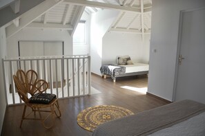 Quarto estilo loft com teto inclinado, uma cadeira de madeira, um tapete estampado e uma cama com colcha de onças.