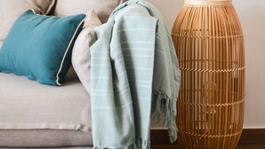 A beige sofa with a teal pillow and a green throw blanket. - Superb T3 Duplex, lagoon-side (Collectivité de Saint-Martin)