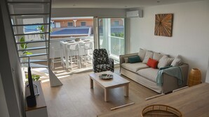 A modern living room with a sofa, coffee table, and a dining area with chairs and a table. - Superb T3 Duplex, lagoon-side (Collectivité de Saint-Martin)