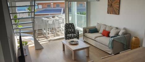 A modern living room with a sofa, coffee table, and a dining area with chairs and a table.