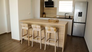 A modern kitchen with a central island, bar stools, a stainless steel refrigerator, and a window above the sink. - Superb T3 Duplex, lagoon-side (Collectivité de Saint-Martin)