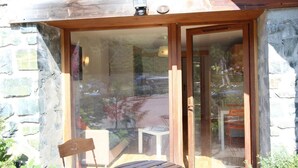 Puerta de vidrio con marco de madera que da a un espacio con una mesa y una silla.