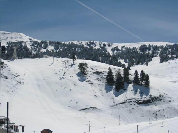 Un paysage de montagne enneigé, avec des remontées mécaniques et un ciel dégagé.