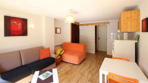Un espacio habitable compacto con sofá, una pequeña mesa y una zona de kitchenette.