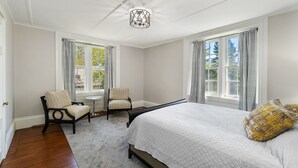 A bedroom with a large bed, two chairs, a small table, and a chandelier. - NEW! Historic Townhome - Live among the Mansions 3BR (Newport)
