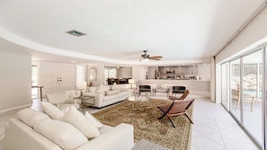 Relax in this spacious living area with a high ceiling, featuring a plush sofa set, dining table, and kitchen area.