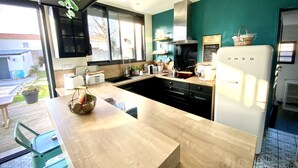 Eine moderne Küche mit Holzarbeitsplatte, schwarzen Schränken und einem weißen Kühlschrank.