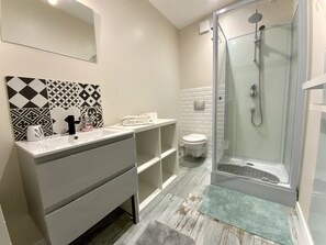 A modern bathroom with a glass-enclosed shower, a white sink with a black faucet, and patterned tiles on the wall.