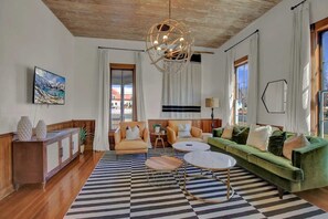 Ein modernes Wohnzimmer mit Schachbrettfußboden, einem grünen Sofa, einem runden Couchtisch und einer außergewöhnlichen Deckenleuchte.