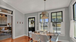 A dining area with a wooden table, white chairs, and a hanging light fixture. - Luxury Stay Right Off Central Main St - Hot Tub! (Fredericksburg)