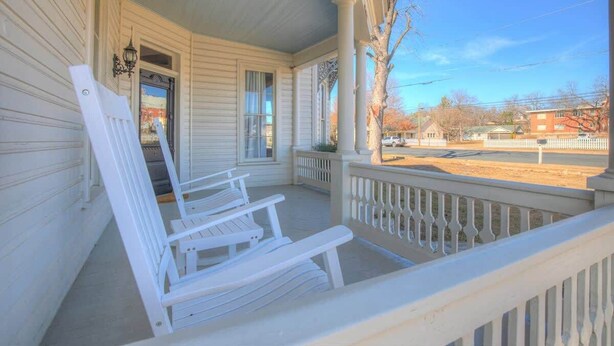 A porch with white wooden chairs and a white railing. - Luxury Stay Right Off Central Main St - Hot Tub! (Fredericksburg)