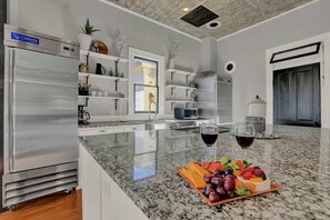 Een moderne keuken met een granieten aanrecht, roestvrijstalen apparatuur en een fruitschaal.