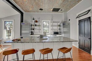 Une cuisine moderne avec un îlot central, des meubles blancs et une porte en bois foncé.