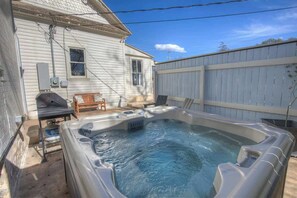 Un jacuzzi dans un jardin, avec une maison et une clôture en bois.
