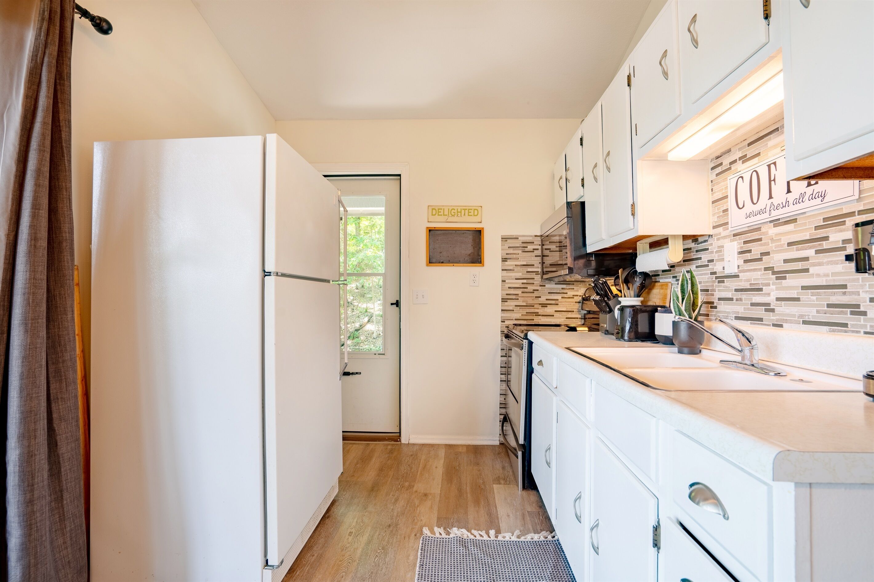 A modern kitchen with white cabinets, a built-in oven, and a backsplash with a mosaic tile design.