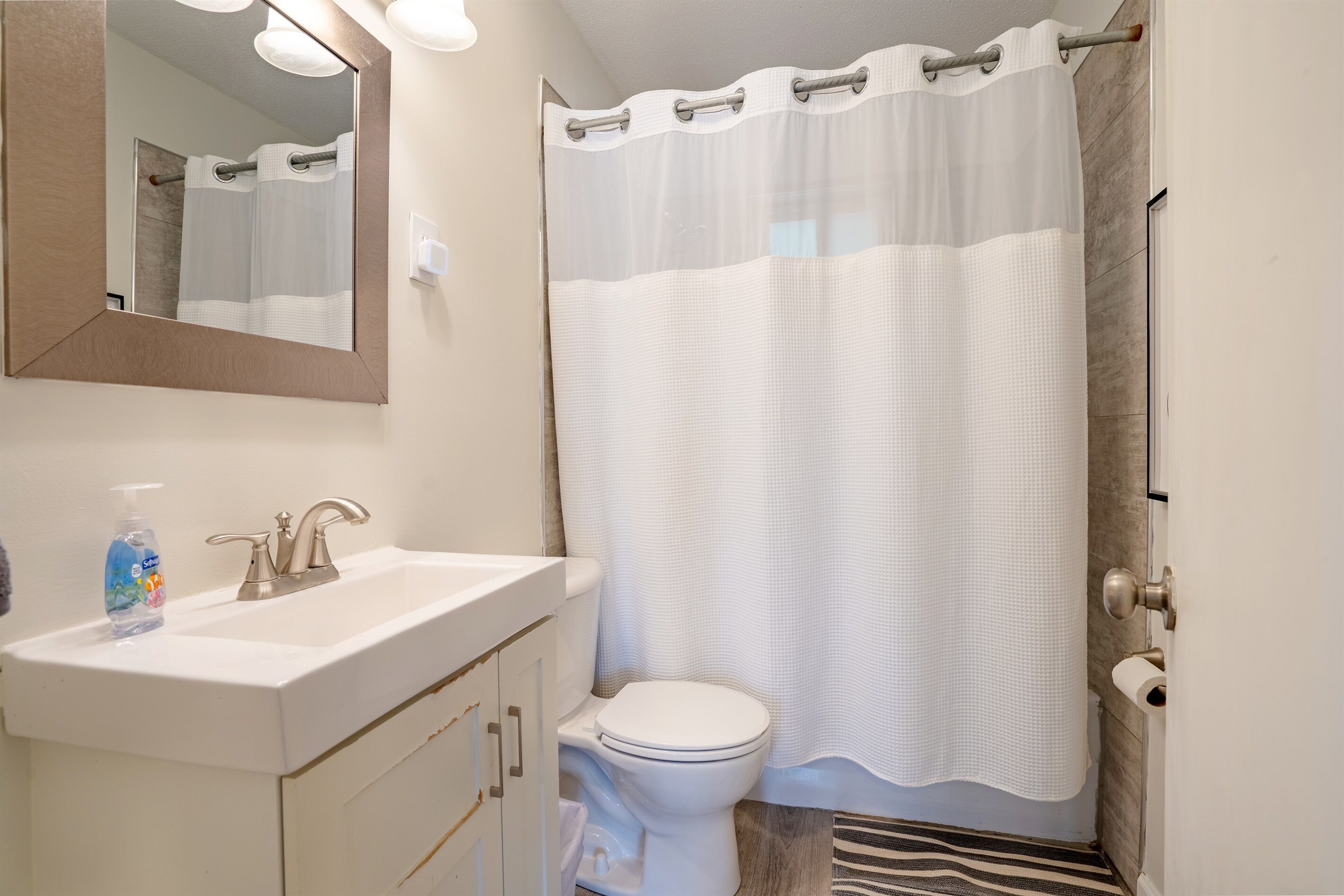 A bathroom with a white sink, mirror, and toilet.