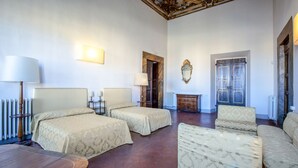 Ein Hotelzimmer mit zwei Betten, einem Schlafsofa, einem Tisch und einem Spiegel.