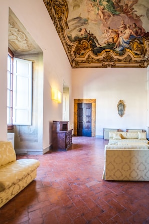 Een ruime kamer met een groot bed, een bank en een open haard.