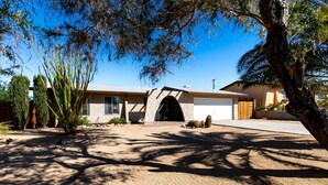 A modern house with a garage, a driveway, and a well-maintained lawn. - Eternity's Edge -Hike/Stargaze, Peaceful, Polished (Twentynine Palms)