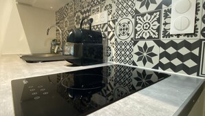 Een keuken met een zwart inductiekookveld, een waterkoker en een witte kast.