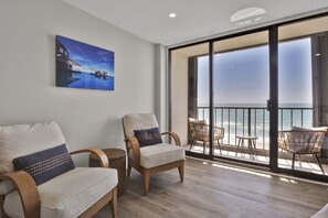 Enjoy the ocean view from the balcony, featuring a comfortable seating area with two chairs and a table.