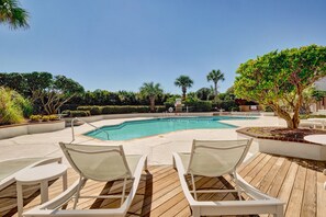 Relax by the serene pool surrounded by lush greenery and palm trees.