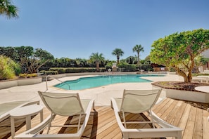Relax by the serene pool surrounded by lush greenery and palm trees.