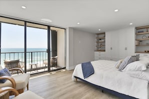 Relax in this serene bedroom with a large bed, balcony, and ocean views.