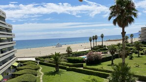 A view of a beach with palm trees and a well-maintained lawn from a balcony. - T2 CABIN with terrace and exceptional sea view (Canet-en-Roussillon)