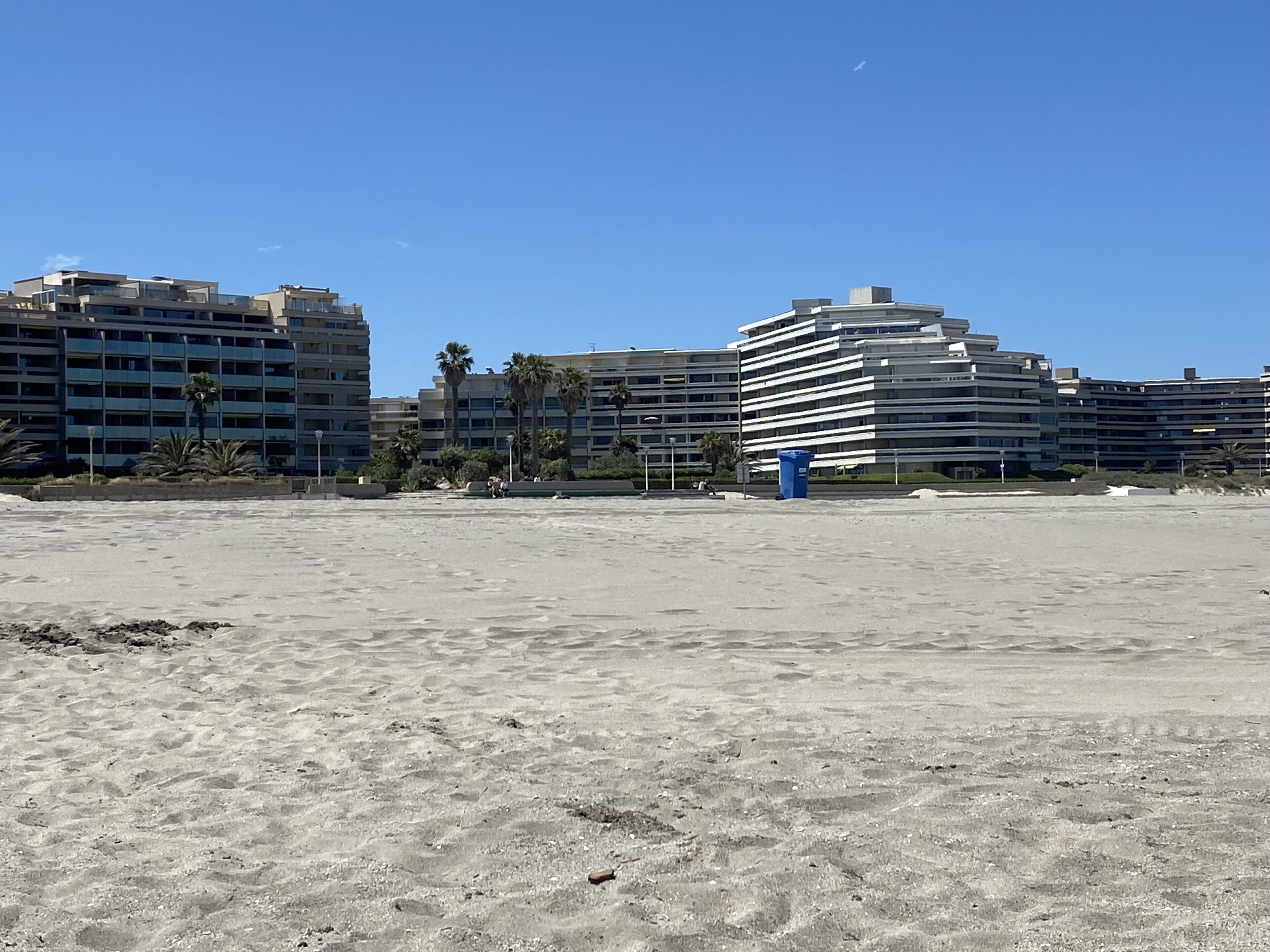 A sandy beach with modern buildings in the background.