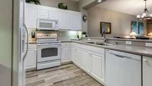 A modern kitchen with white cabinetry, a built-in microwave, an oven, and a dishwasher. - Beautiful Resort in Quiet, Gated Community w Pool (Port Charlotte)
