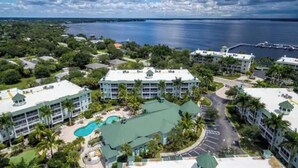 A resort with multiple buildings, a swimming pool, and a marina in the background. - Beautiful Resort in Quiet, Gated Community w Pool (Port Charlotte)
