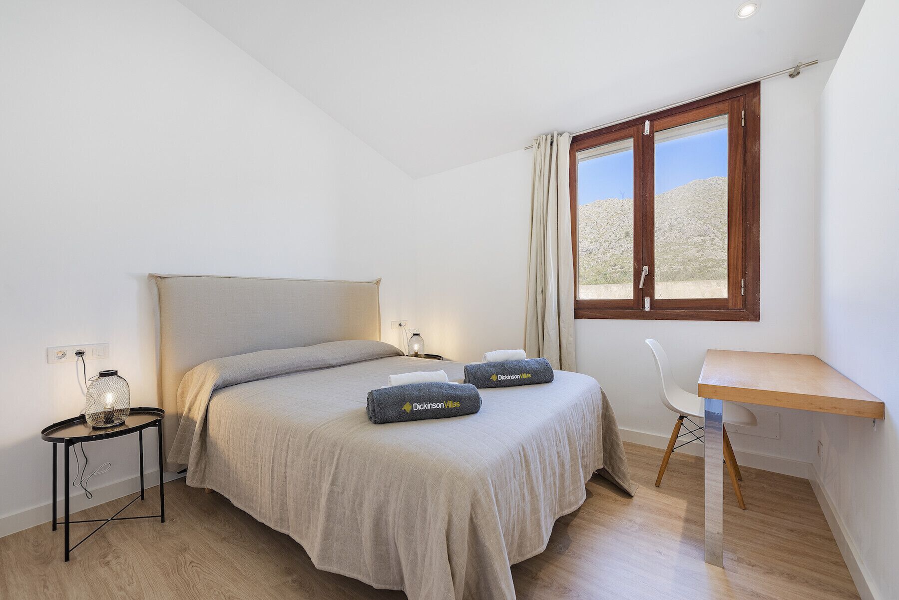 Ein Schlafzimmer mit einem Bett, einem Nachttisch, einer Lampe und einem Schreibtisch mit Stuhl.