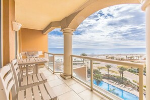 Enjoy the ocean view from this balcony with a table and chairs, overlooking the pool and sandy beach.