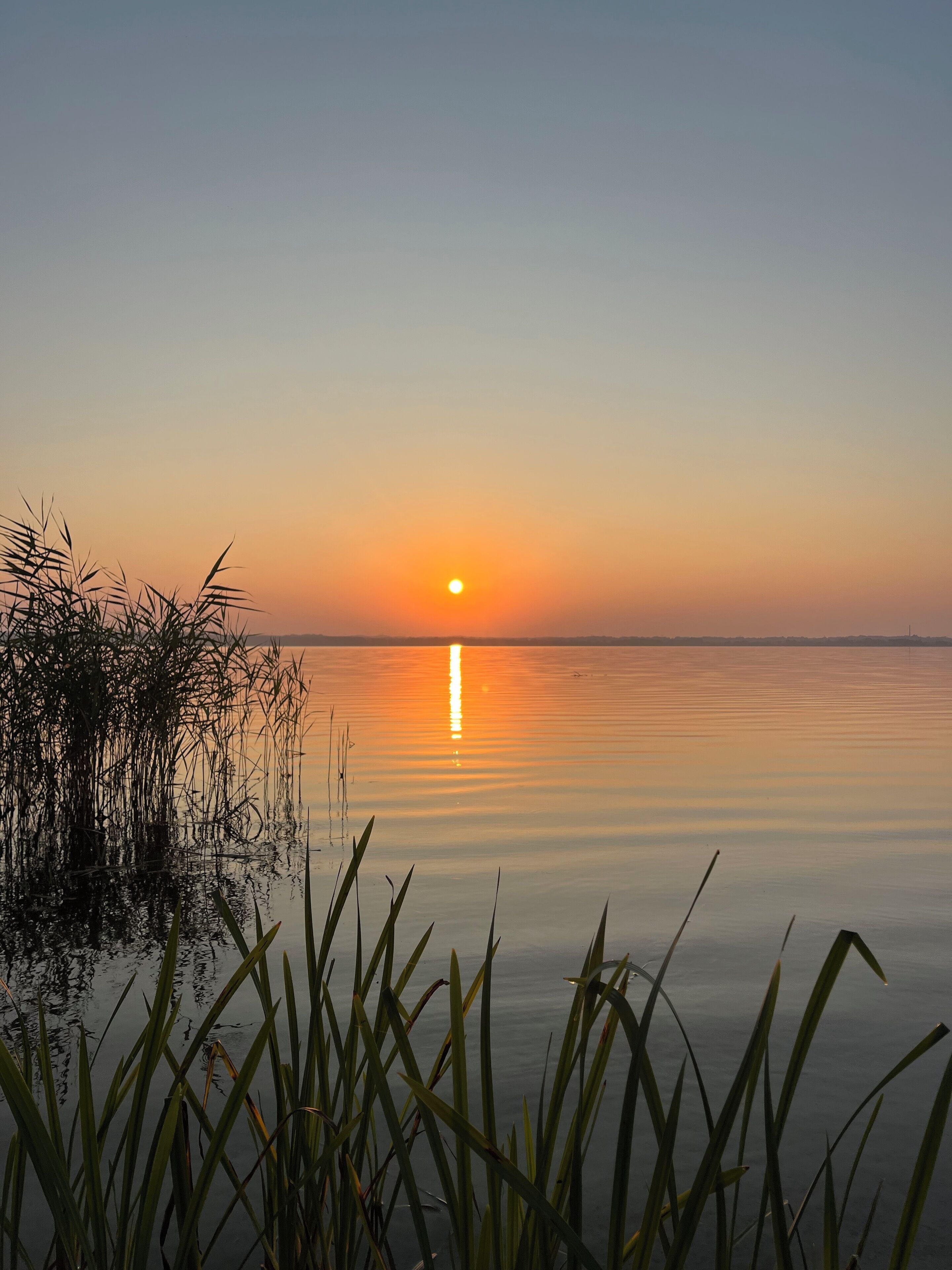 Een rustig meer bij zonsondergang met een heldere lucht.