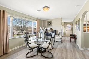 Enjoy meals in this dining area with a round table and four chairs, surrounded by a large window offering a view of the outdoors.