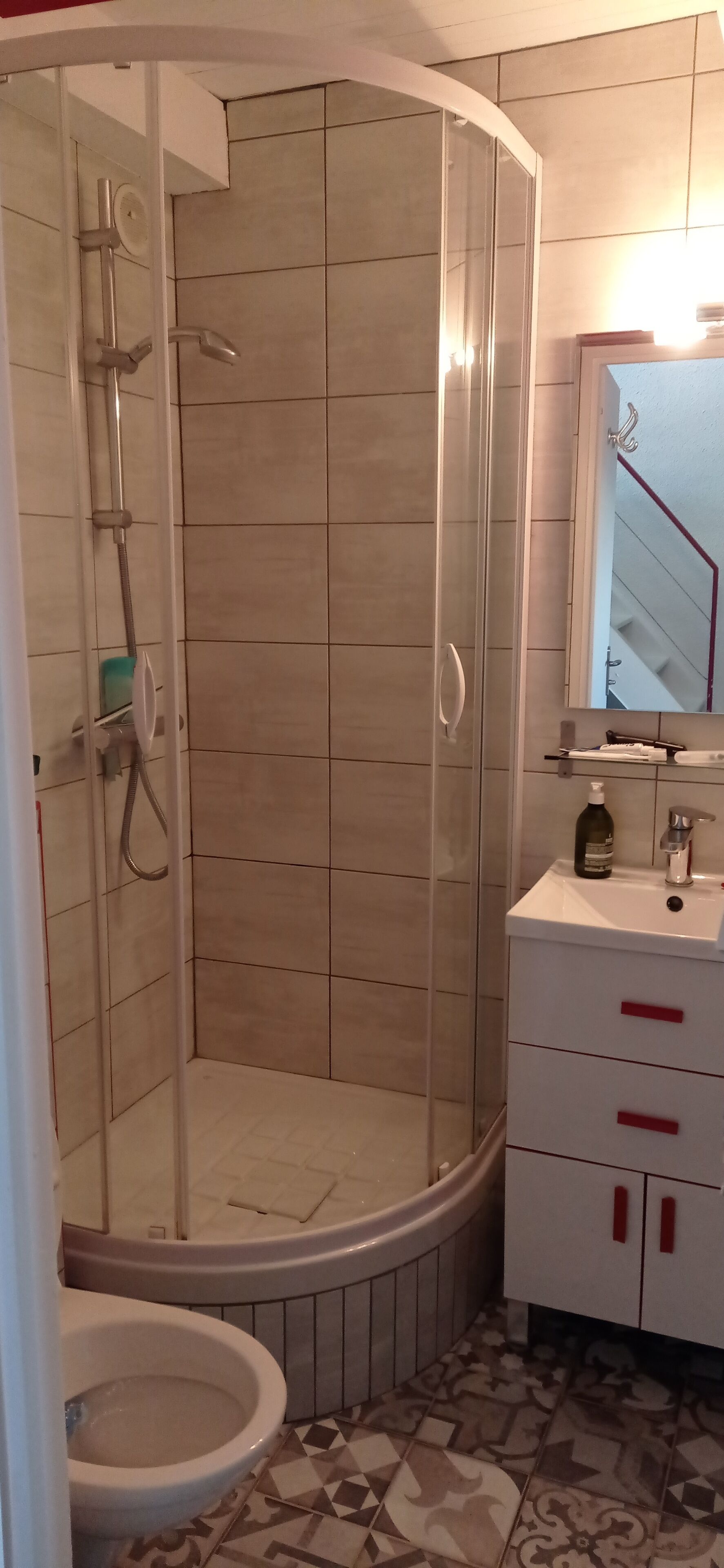 A bathroom with a glass-enclosed shower, a toilet, and a sink with a mirror above it.