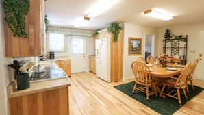 A kitchen with wooden cabinets, a dining table with chairs, and a refrigerator.