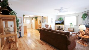 A cozy living room with a brown sofa, wooden floor, and a ceiling fan.