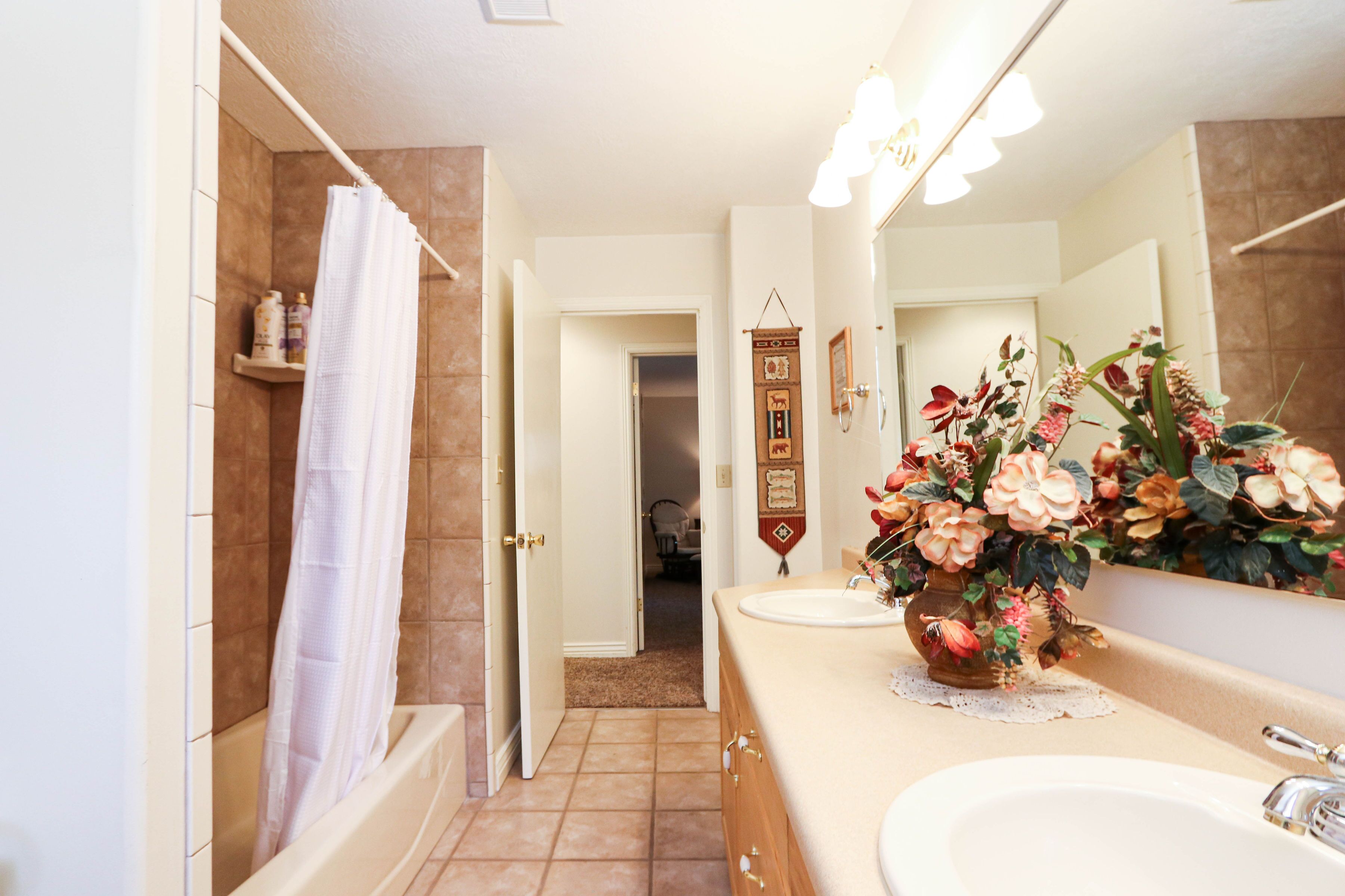 A bathroom with a bathtub, a sink, a mirror, and a shower curtain.