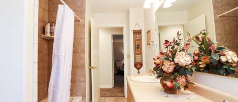 A bathroom with a bathtub, a sink, a mirror, and a shower curtain.