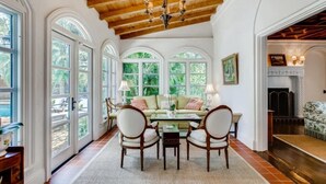 A dining area with a wooden ceiling, a chandelier, and a sofa set.