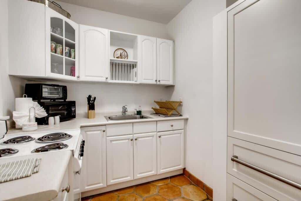 Una cocina compacta con armarios blancos, estufa, microondas y pileta.