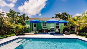 A swimming pool with a green house in the background, surrounded by palm trees and a clear sky. - Key Lime Cottage - Bask Poolside in a Historic Flamingo Park Gem (West Palm Beach)