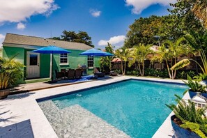 A swimming pool with a patio area, umbrellas, and tropical plants. - Key Lime Cottage - Bask Poolside in a Historic Flamingo Park Gem (West Palm Beach)