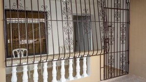 A balcony with a wrought iron gate and white balustrade, leading to a room with a window and a door. - Small and cozy apartment perfect for working (Bouvet Island)