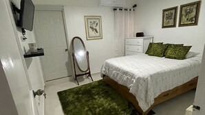 A bedroom with a bed, a dresser, a television, a mirror, and a ceiling fan. - Small and cozy apartment perfect for working (Bouvet Island)